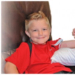 a boy with a red shirt sitting in a chair