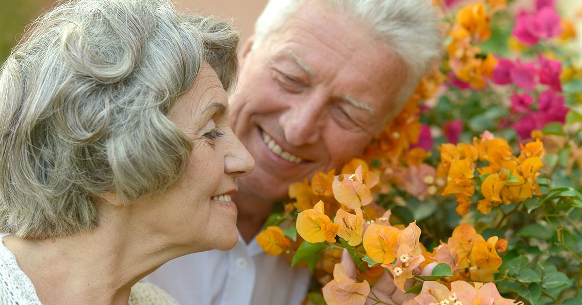 Older couple breathing easy, smelling flowers