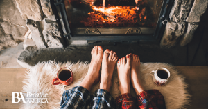 two people warming their feet by the fire